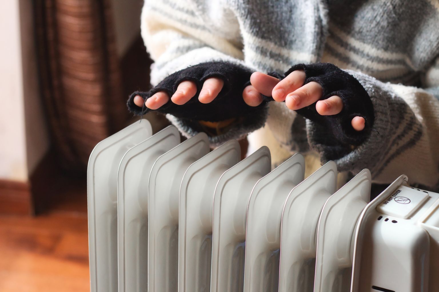 Persoon warmt zijn handen boven een radiator