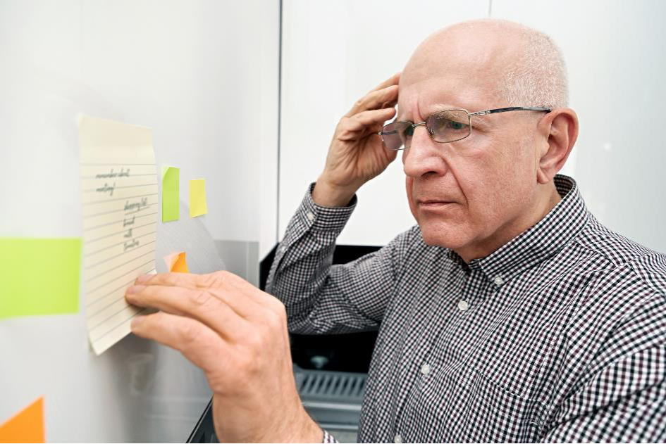 Un anciano con demencia mira sus notas