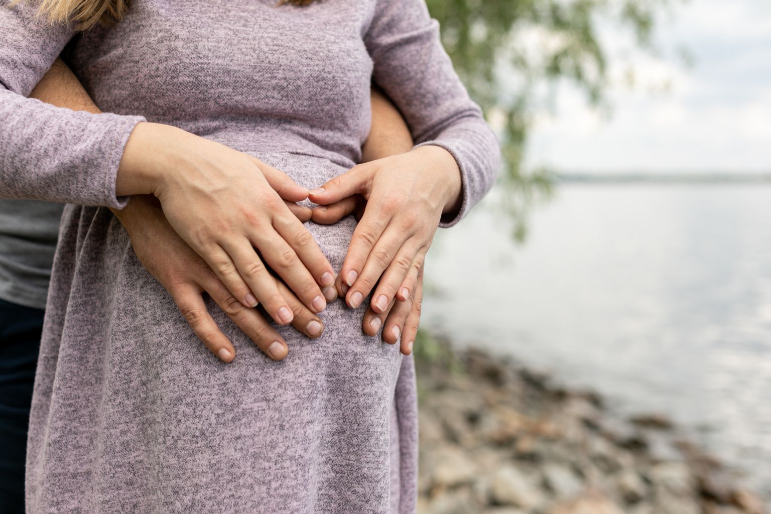 Un par de manos sosteniendo el vientre de una joven embarazada