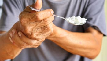 Una persona mayor se coge de la mano mientras come.