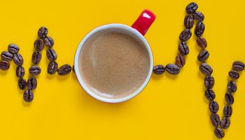 Hartslagimpulslijn met rode koffiekop op gele achtergrond. Coffee Cardio Images.coffee hart