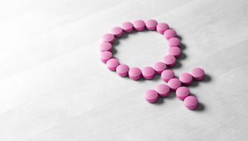 Sex symbol made of pink red pills or tablets on wooden table.