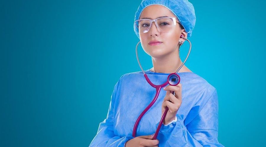 Um grande plano de uma mulher num vestido de hospital segurando um estetoscópio.