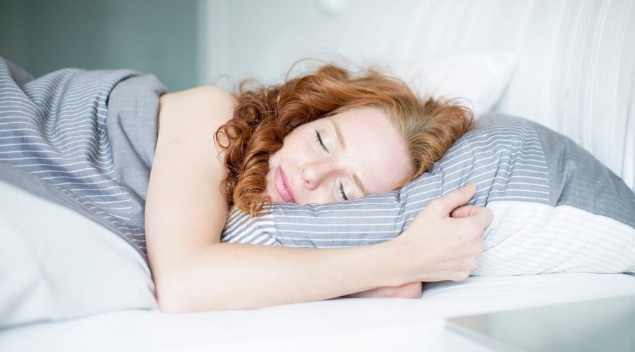 Frau mit roten Haaren schläft im Bett.