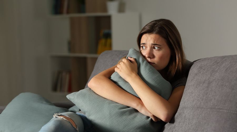 Zuhause erschrecken Teenager mit Kissen, die auf einer Couch im Wohnzimmer sitzen 