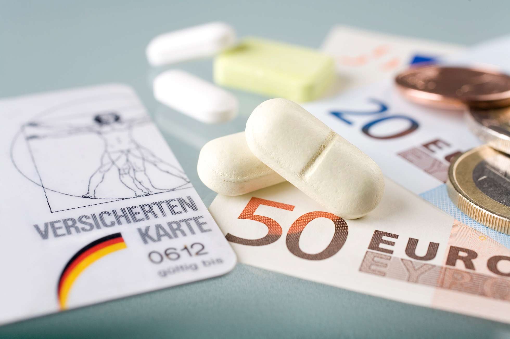 Un gros plan sur une carte d'assuré d'Allemagne, de l'argent liquide et des médicaments.
