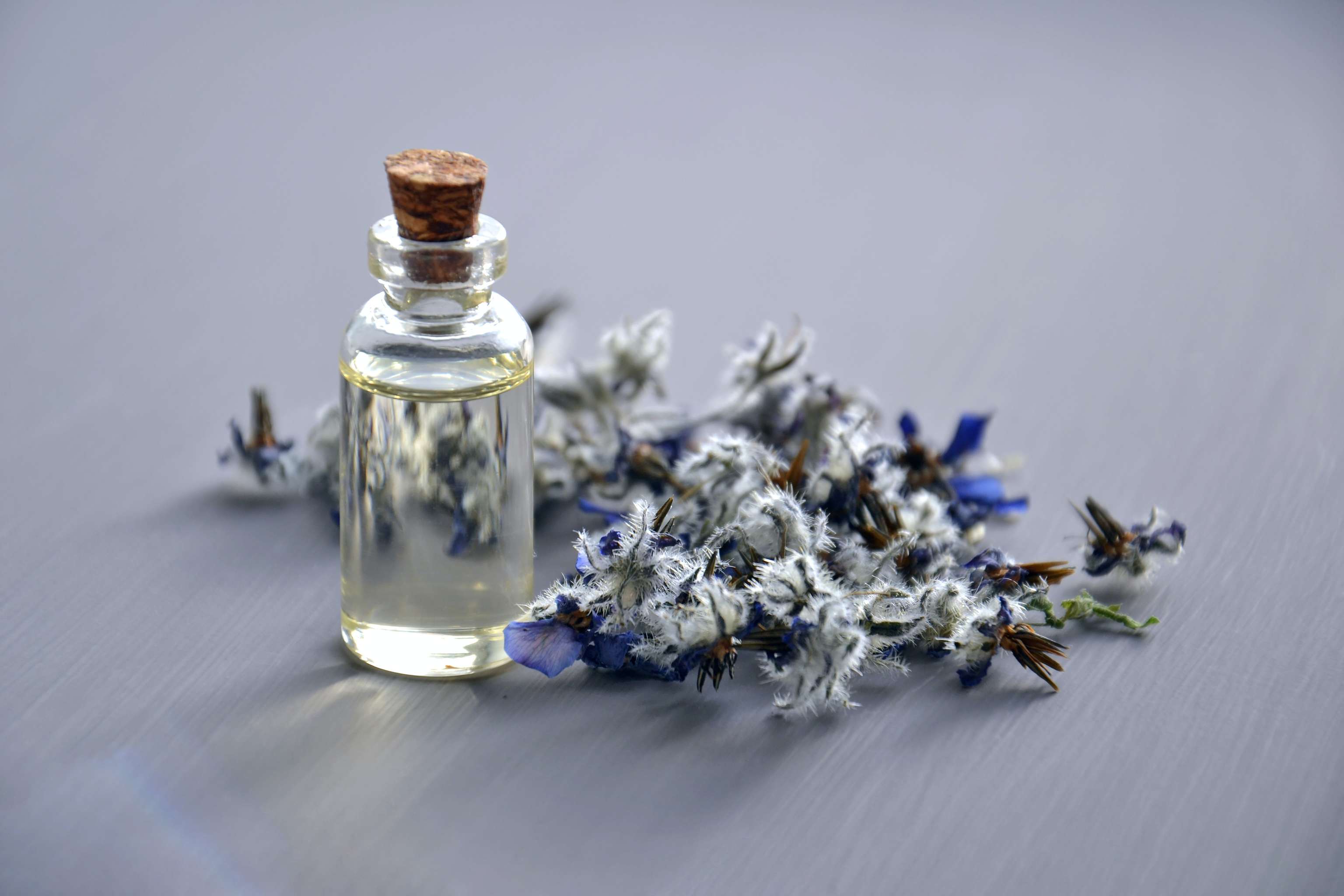 Blüten mit kleiner Glasflasche. Drinnen ist ein aromatisches Öl.