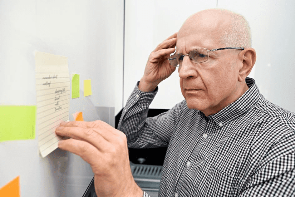 Bejaarde man met dementie kijkt naar aantekeningen