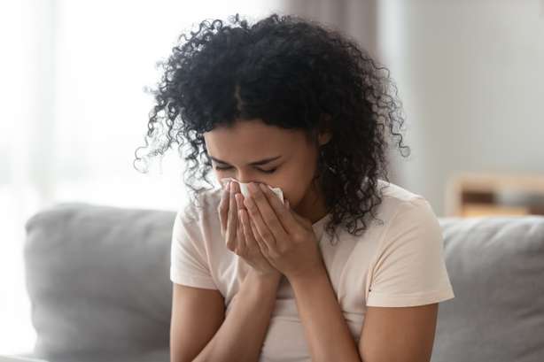 Frau mit allergischen Symptomen. Ill verärgerte afrikanische Frau, die die laufende Nase bläst, bekam Grippe, die sich im Gewebe nieder schlug, kranke allergische schwarze Frau mit allergischen Symptomen, die eine Serviette zu Hause hustete, Heufieber-Konzept