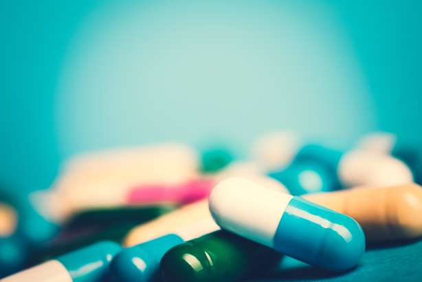 Arzneimittel-grüne und gelbe Tabletten oder Kapseln auf blauem Hintergrund mit Kopienraum.Verschreibung von Arzneimitteln zur Behandlung. Arzneimittel zur Heilung in Behältnissen für die Gesundheit. Antibiotika