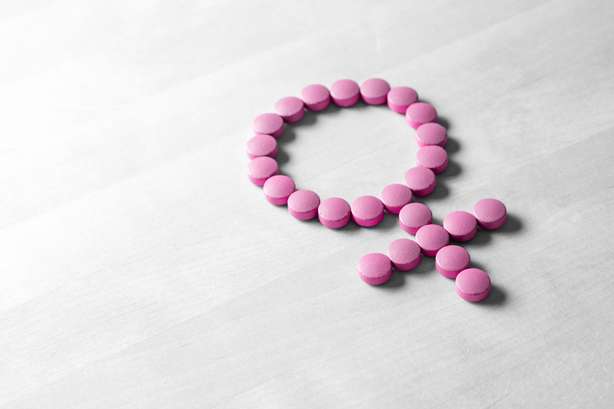 Geschlechtssymbol aus rosafarbenen roten Pillen oder Tabletten auf Holztisch. Geschlechtssymbol aus rosafarbenen roten Pillen oder Tabletten auf Holztisch.