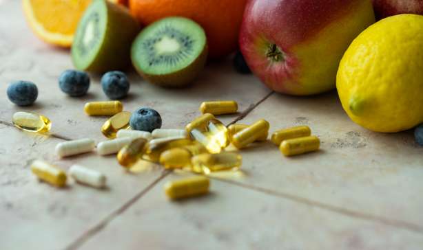 NatĂĽrliche FrĂĽchte und Multivitaminkapseln. NatĂĽrliche und synthetische Vitaminquellen Nahaufname von FrĂĽchten und Vitaminkapseln