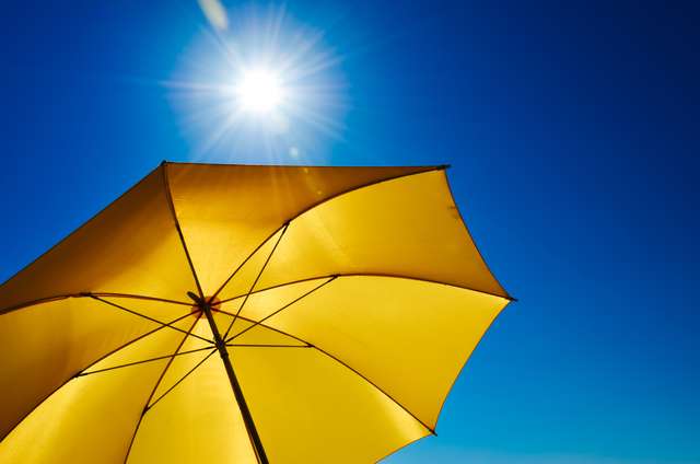 Gelber Sonnenschirm mit blauem Himmel