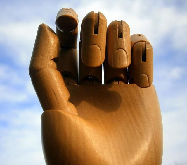 Close up of wooden hand with open sky in background.