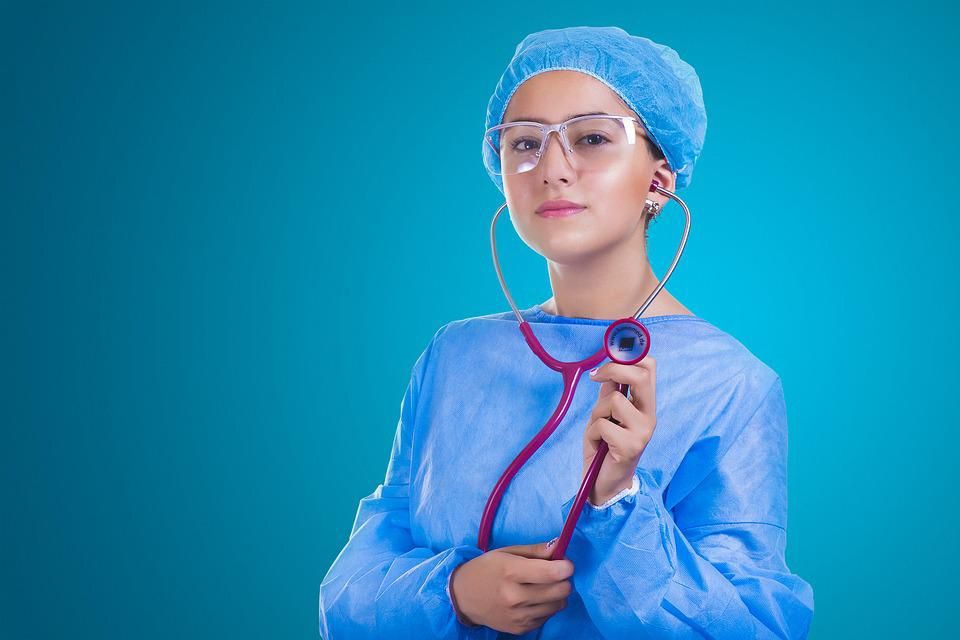 A close-up of a woman in a hospital gown holding a stethoscope.