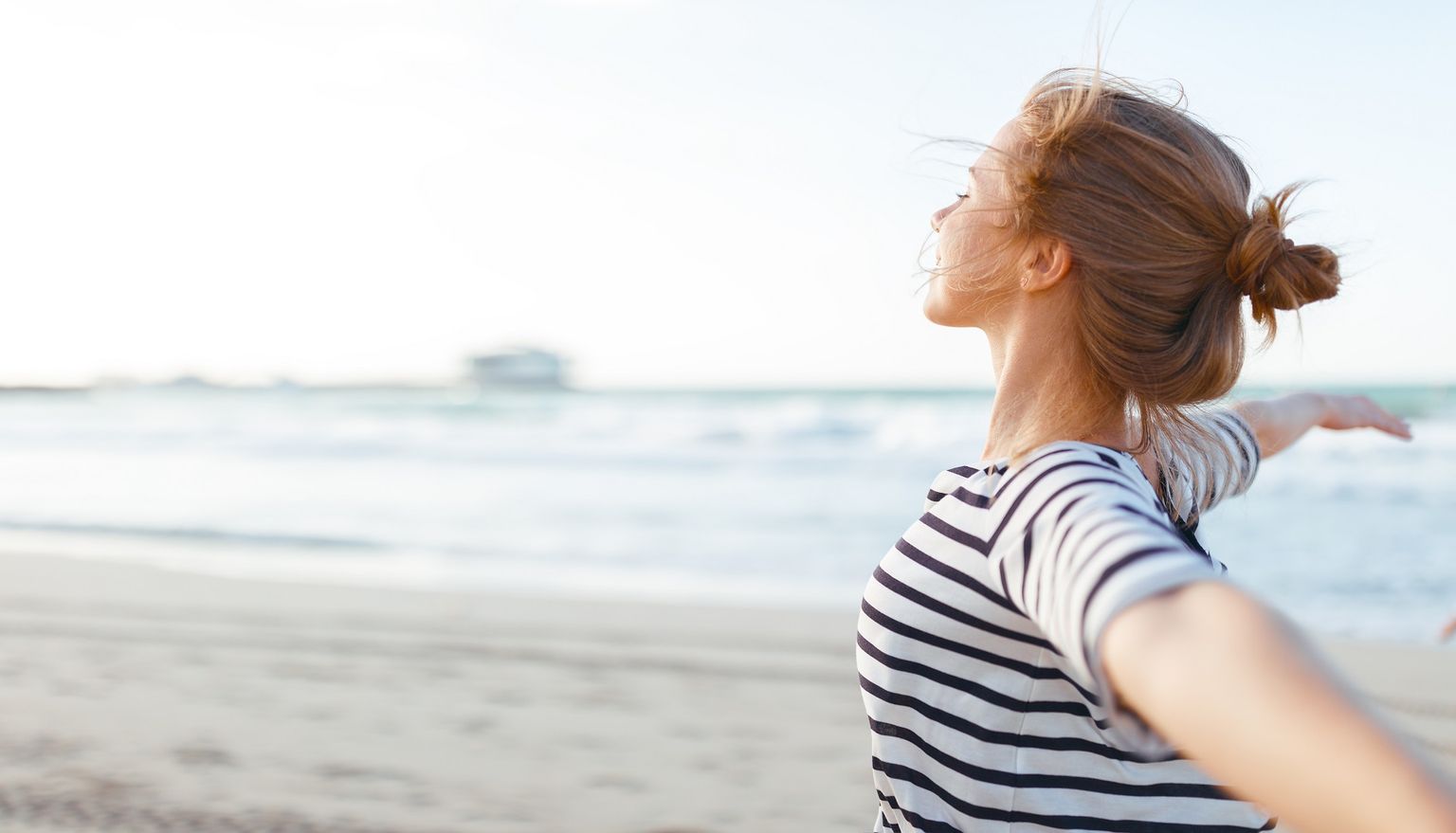 Woman opens arms by the sea and enjoys freedom