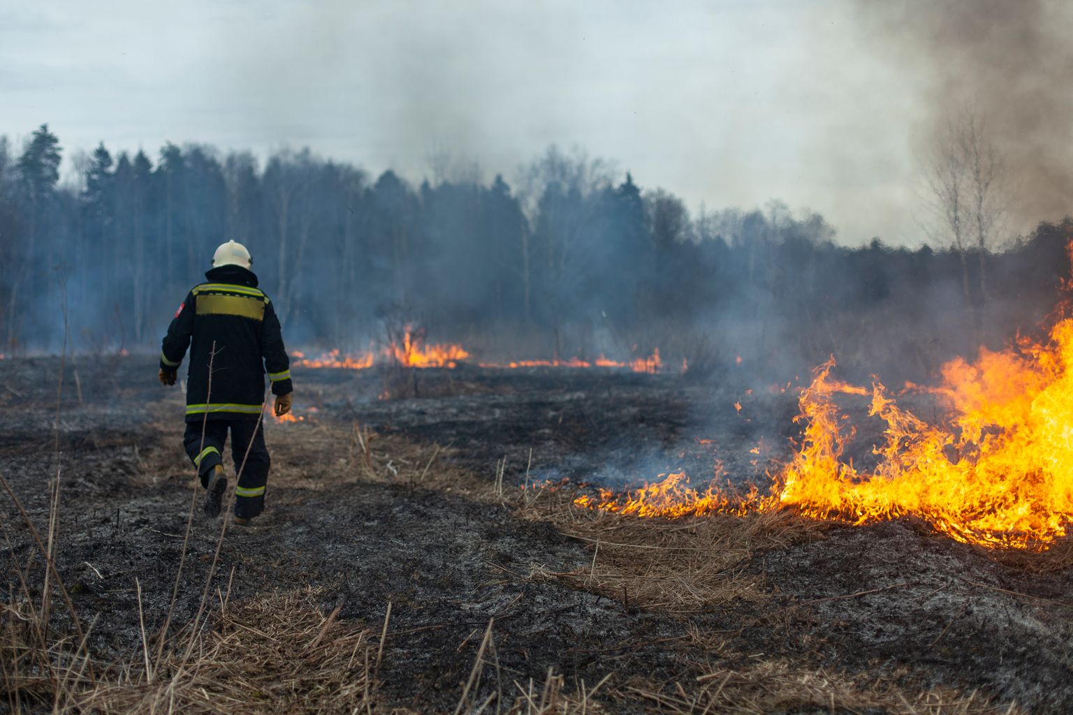 Feuerwehrmann geht durch brennende Landschaft durch