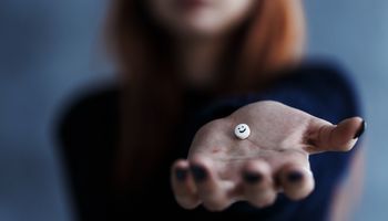 Close up of pill with smiley face in one hand