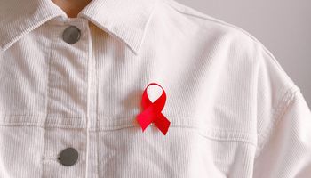A person in a white shirt wears a Red Ribbon, a symbol of solidarity with people infected with HIV and AIDS.