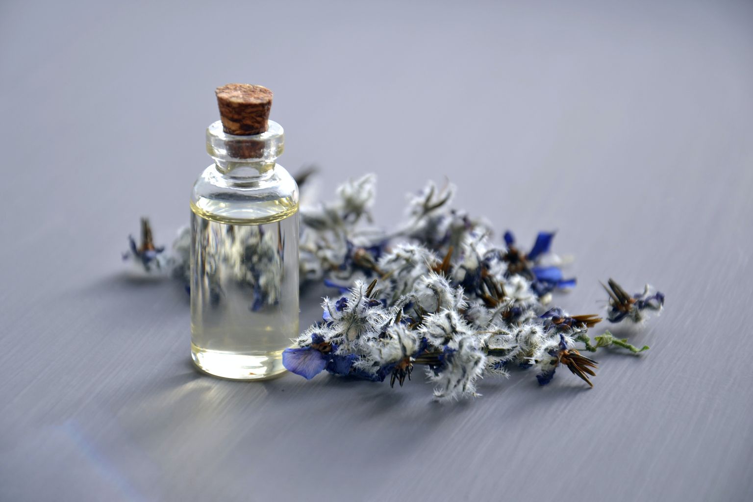 Blüten mit kleiner Glasflasche. Drinnen ist ein aromatisches Öl.