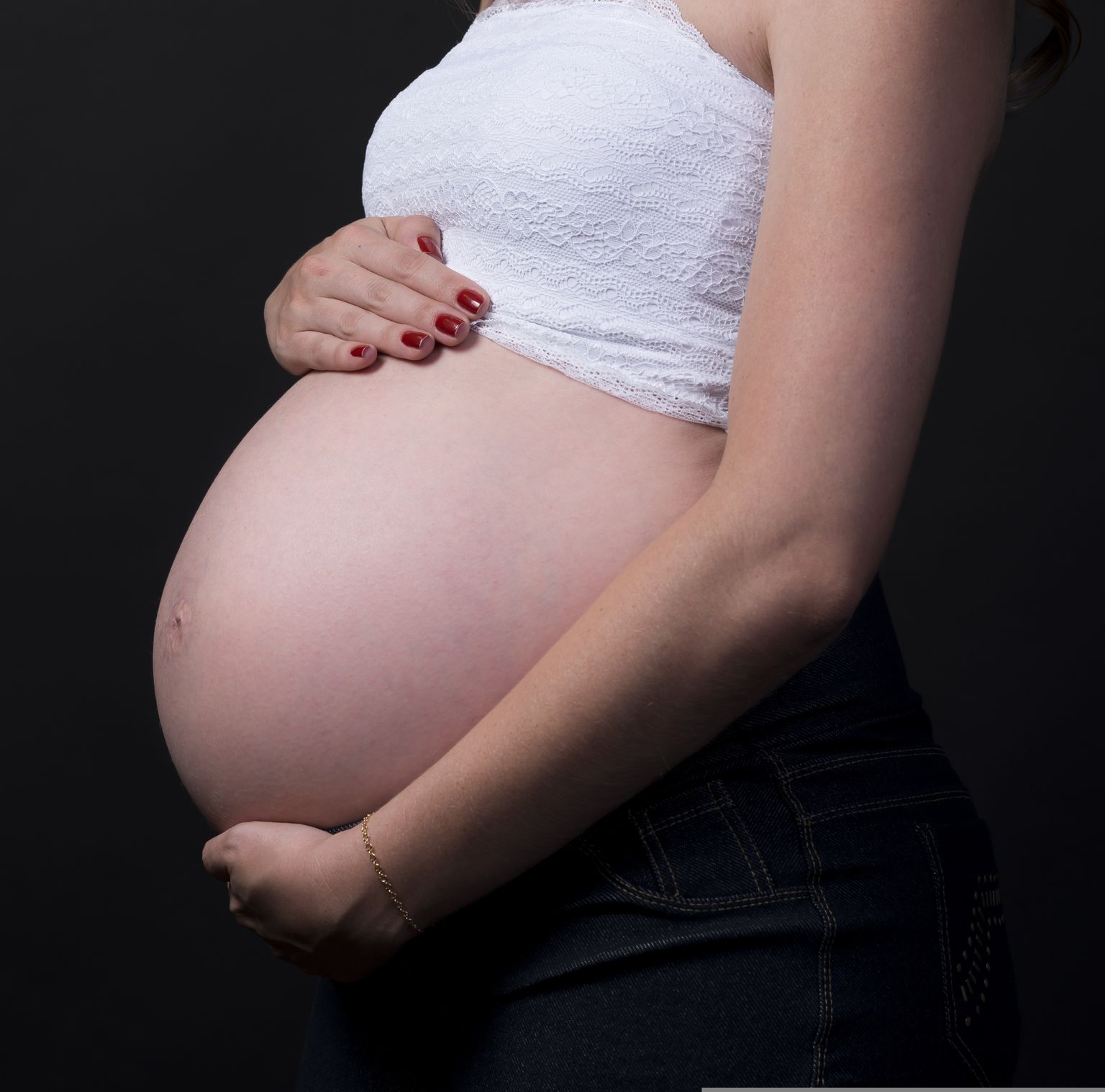 Schwangere Frau hält sich am Bauch