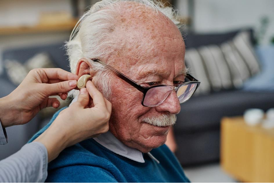 Grande plano de um idoso com um aparelho auditivo