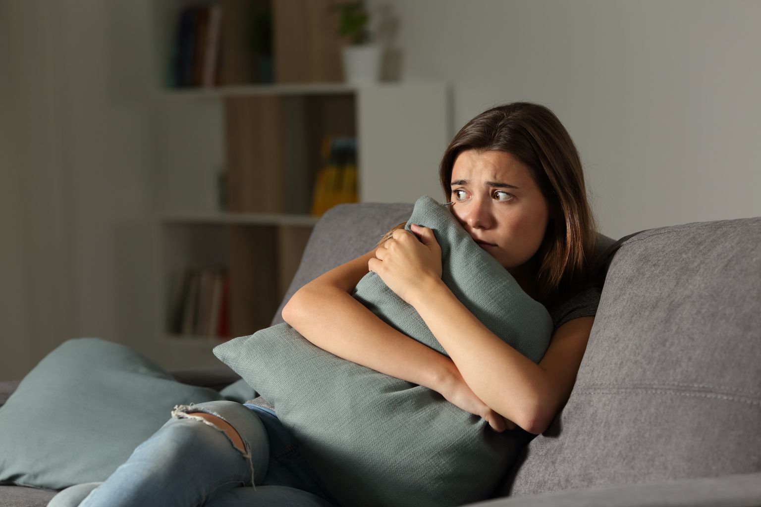 Adolescentes assustados com travesseiros sentados em um sofá na sala de estar 