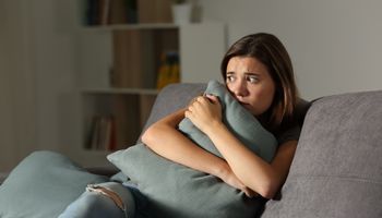 Adolescentes con miedo a casa con almohadas sentados en un sofá en la sala de estar