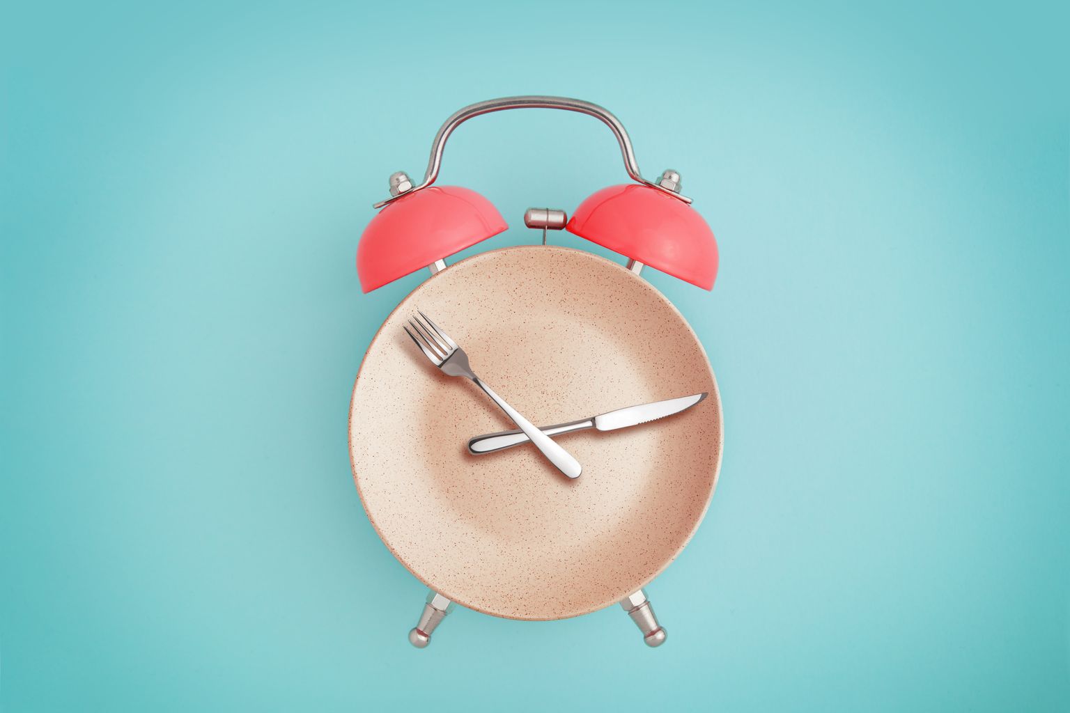 Alarm clock and plate with cutlery . concept of intermittent fasting, lunch, diet and weight loss