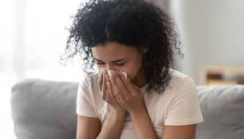 Femme africaine malade et en colère qui se mouche, grippe qui s'est installée dans les tissus, femme noire malade et allergique avec des symptômes allergiques qui tousse dans une serviette à la maison, concept de rhume des foins.
