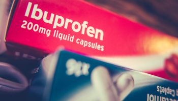 Boîte d'analgésiques prescrits sur ordonnance (ibuprofène et paracétamol) sur une armoire à la maison.