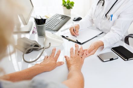 Grande plano de um exame médico. Mulher de meia-idade com artrite mostrando as mãos a uma médica.
