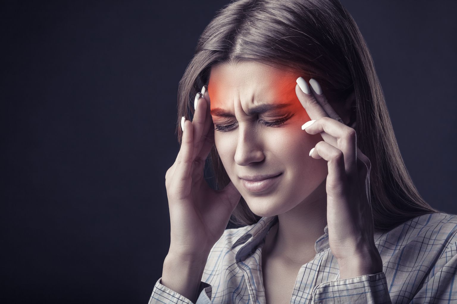 Jeune femme souffrant de maux de tête sur fond sombre. Prise de vue en studio
