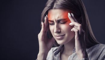 Jeune femme souffrant de maux de tête sur fond sombre. Prise de vue en studio